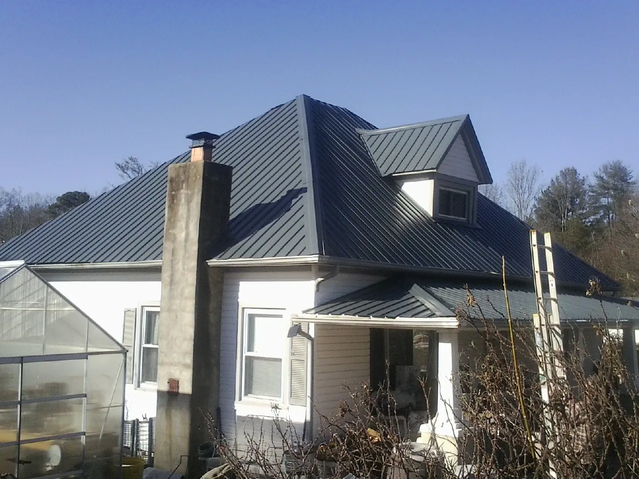 Dark blue standing seam metal roof on a white farmhouse with dormer — Slate & Tile Roof Repair by Roofing Brothers in Scott Bar
