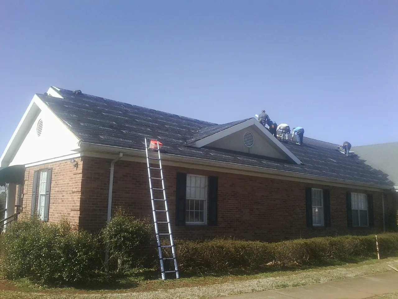 Crew tearing shingles off a brick ranch roof with a ladder set — Metal Roof Repair work by our crew in Scott Bar