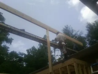 Carpenter setting a ridge beam over a new addition frame — Ice Dam Removal by Roofing Brothers in Scott Bar