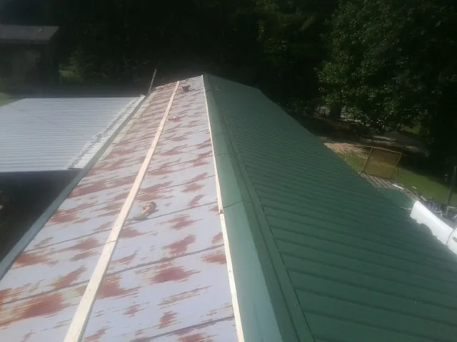 Old rusted panels beside newly installed green metal roofing — Wind Damage Roof Repair by Roofing Brothers in Scott Bar