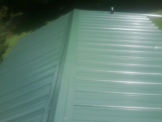 New green metal panels meeting at the ridge of a roof — Flat Roof Repair work by our crew in Scott Bar