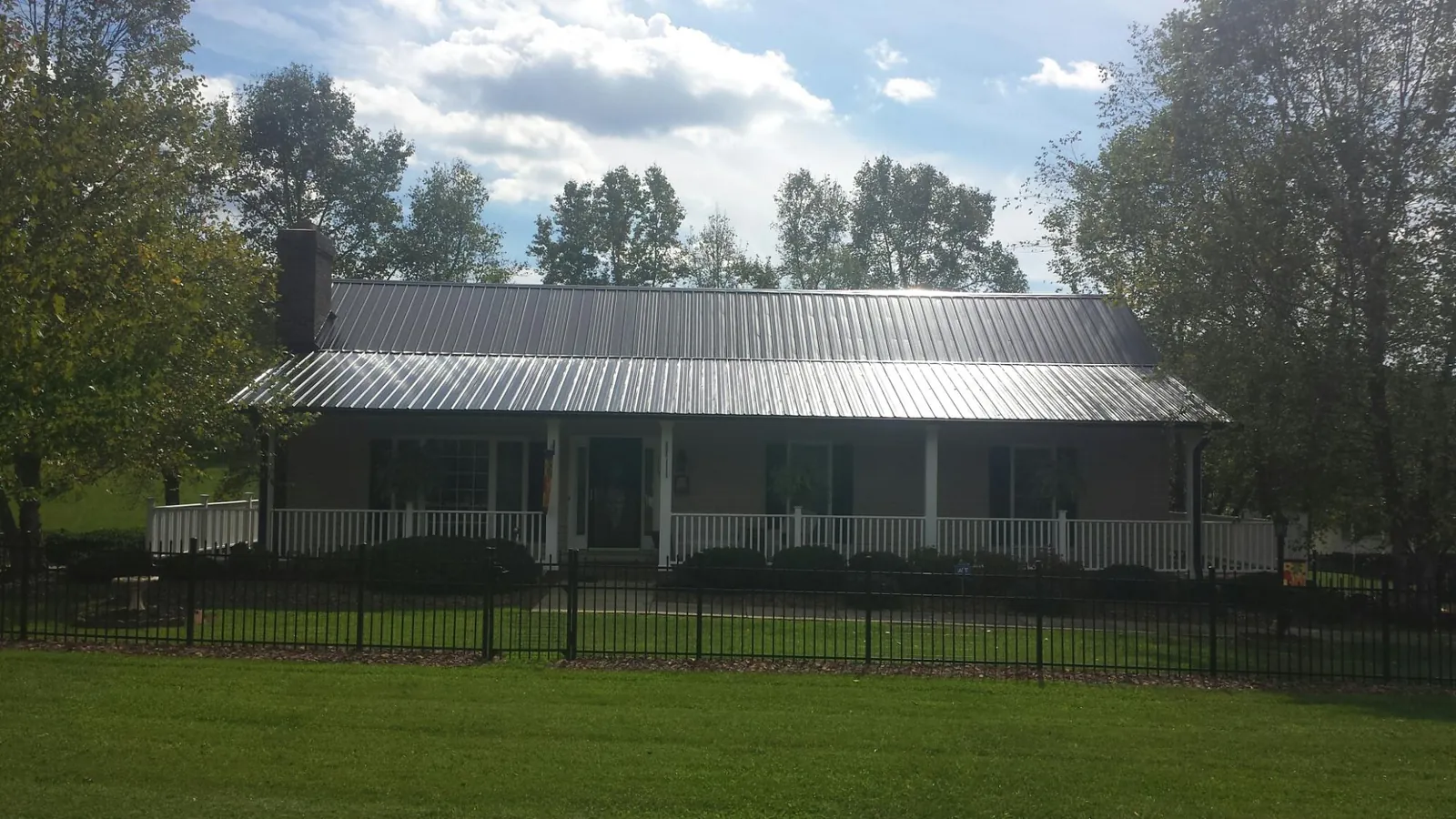 Gray metal roof on a brick ranch with a full width front porch — Gutter Guard Installation work by our crew in Scott Bar