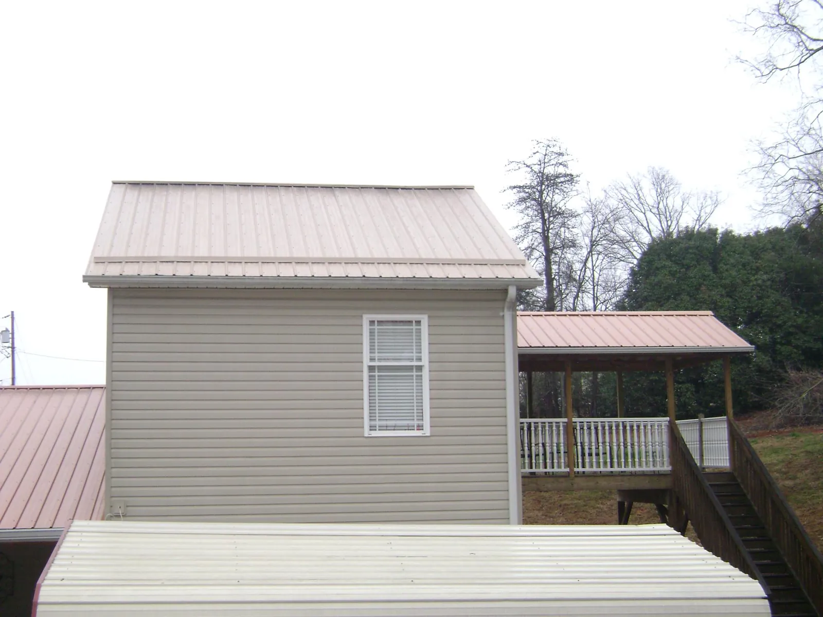 Tan metal roofs on a two story addition and attached porch, from a Roof Replacement job in Scott Bar