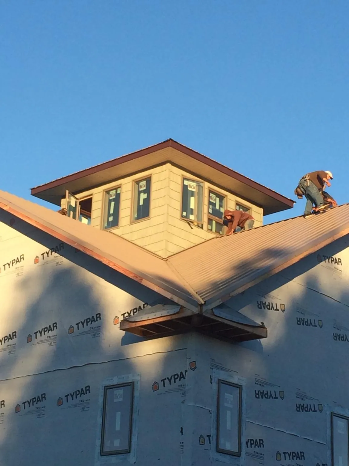 Roofers working around a rooftop cupola on a new metal roof at sunset — Roof Waterproofing in Scott Bar by Roofing Brothers